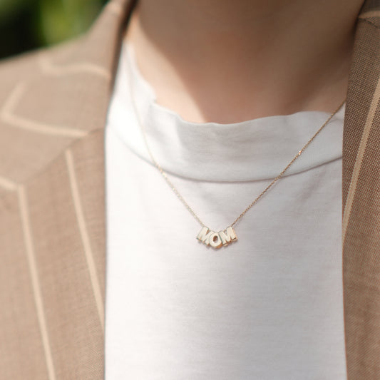 Model trägt eine MOM-Buchstabenkette aus 14k Echtgold.