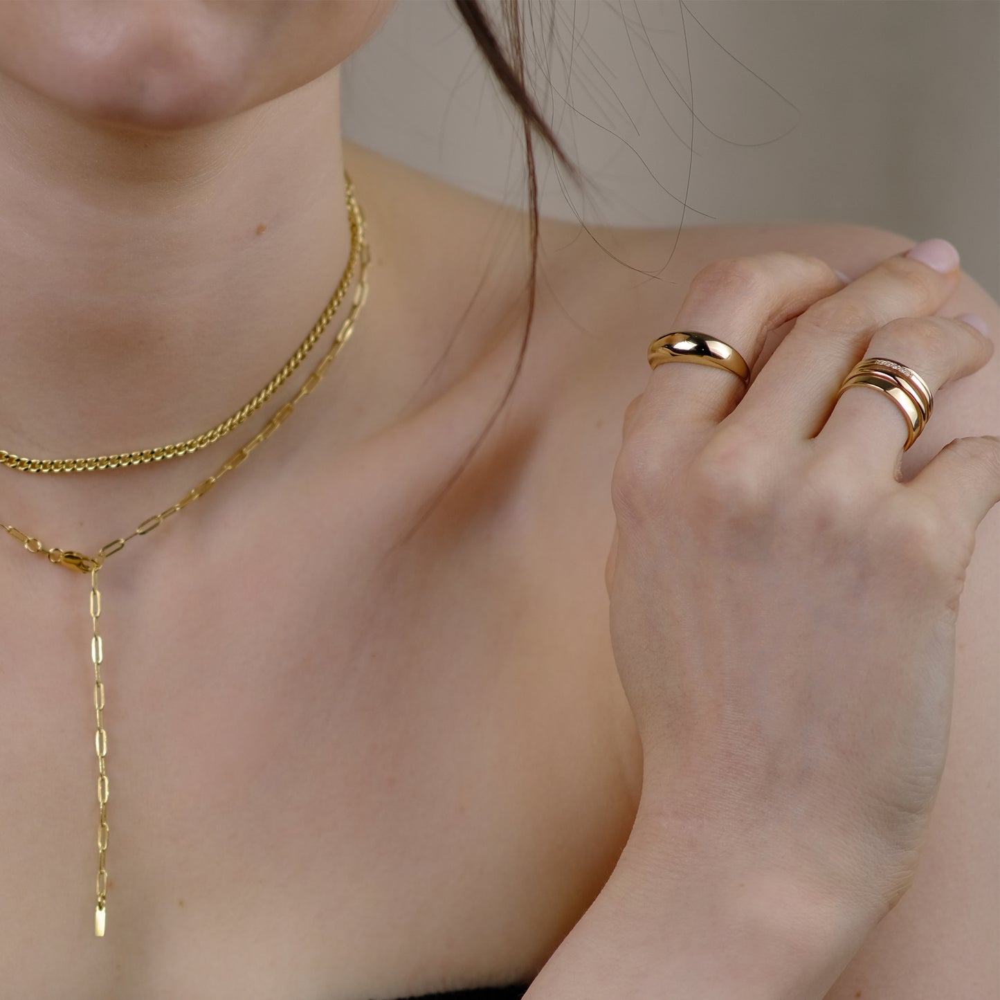 Model hat eine Hand auf ihrer Schulter abgelegt. Sie trägt verschiedene Schmuckstücke der Marke ayu.