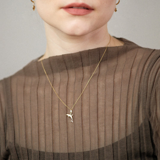 Model trägt eine Kette mit Delfin-Anhänger aus 14k Echtgold.
