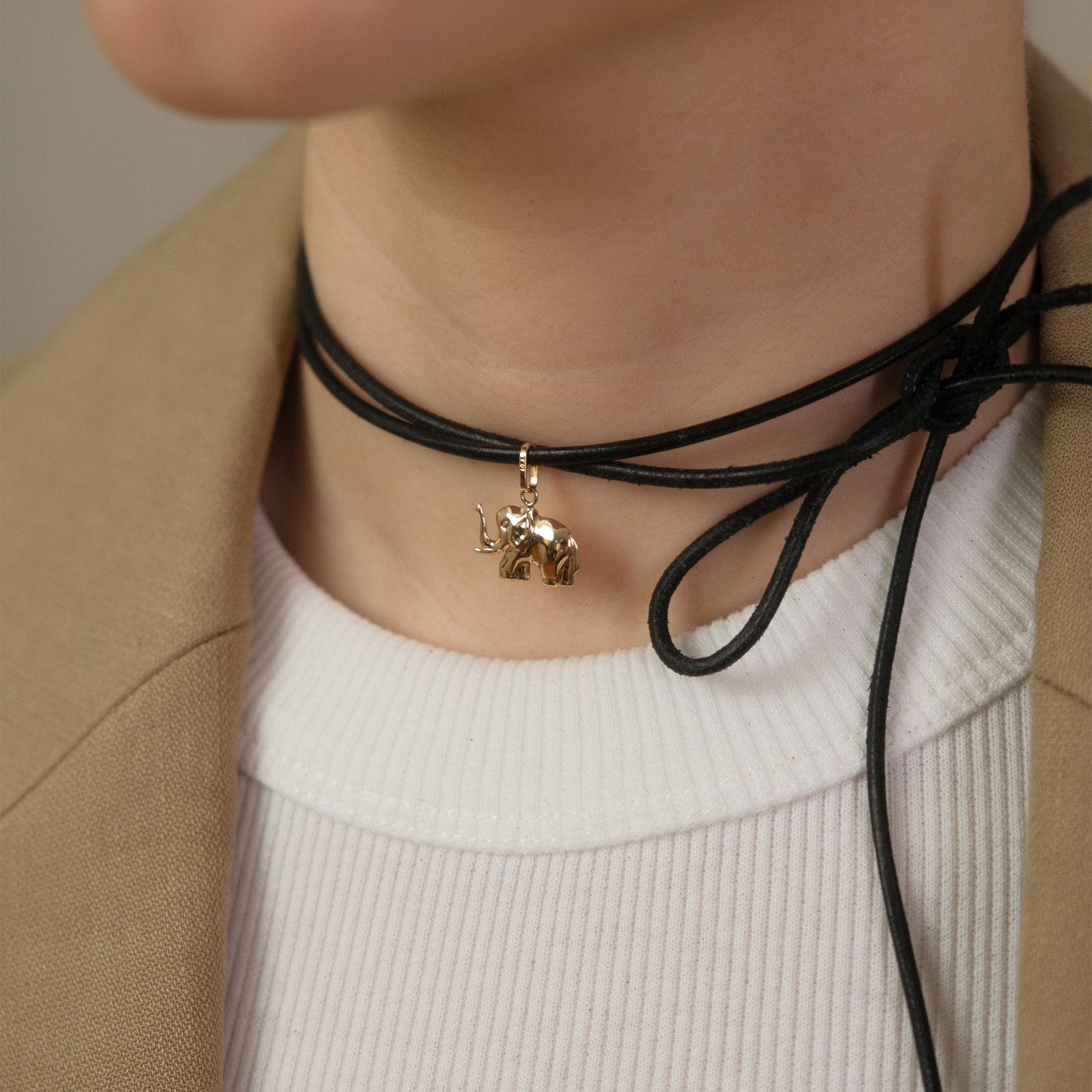 Model trägt einen Elefant-Anhänger aus 14k Echtgold an einem schwarzen Lederband eng um den Hals.