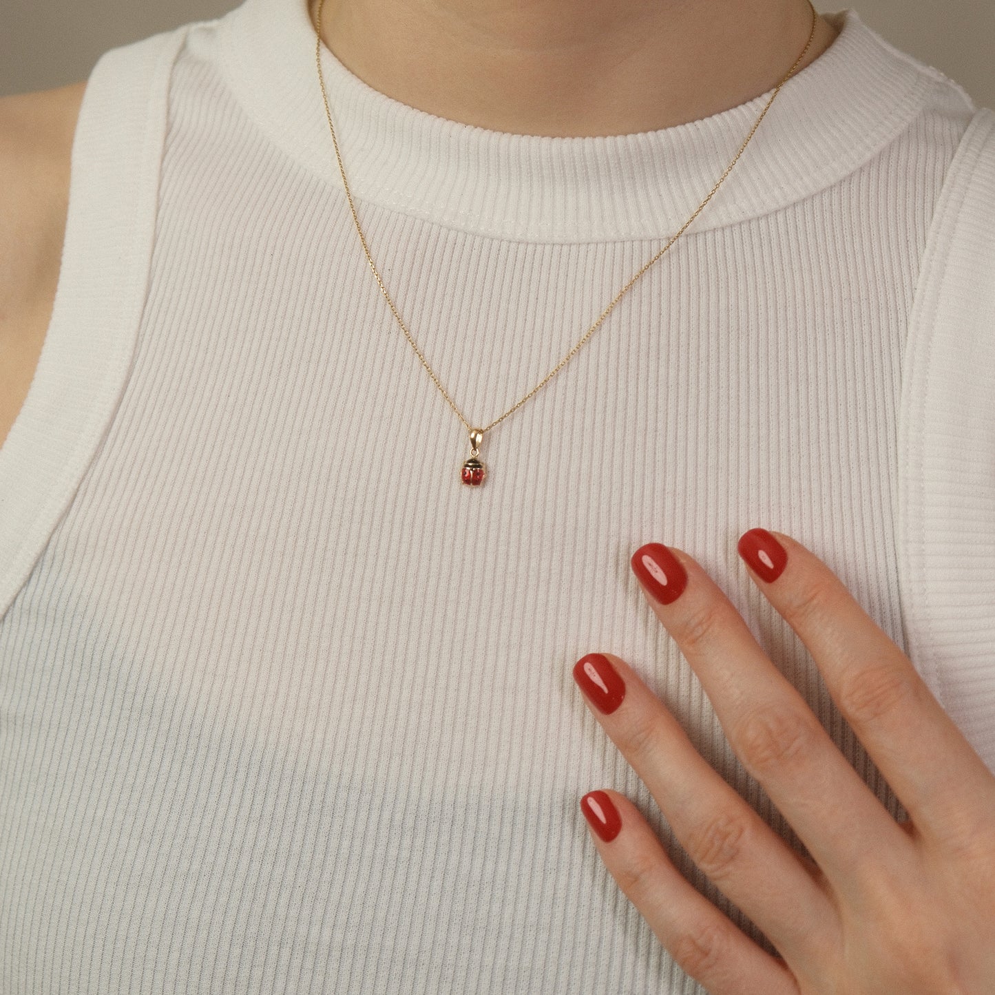 Model trägt eine Kette mit Marienkäfer-Anhänger aus 14k Echtgold über weißem Top.