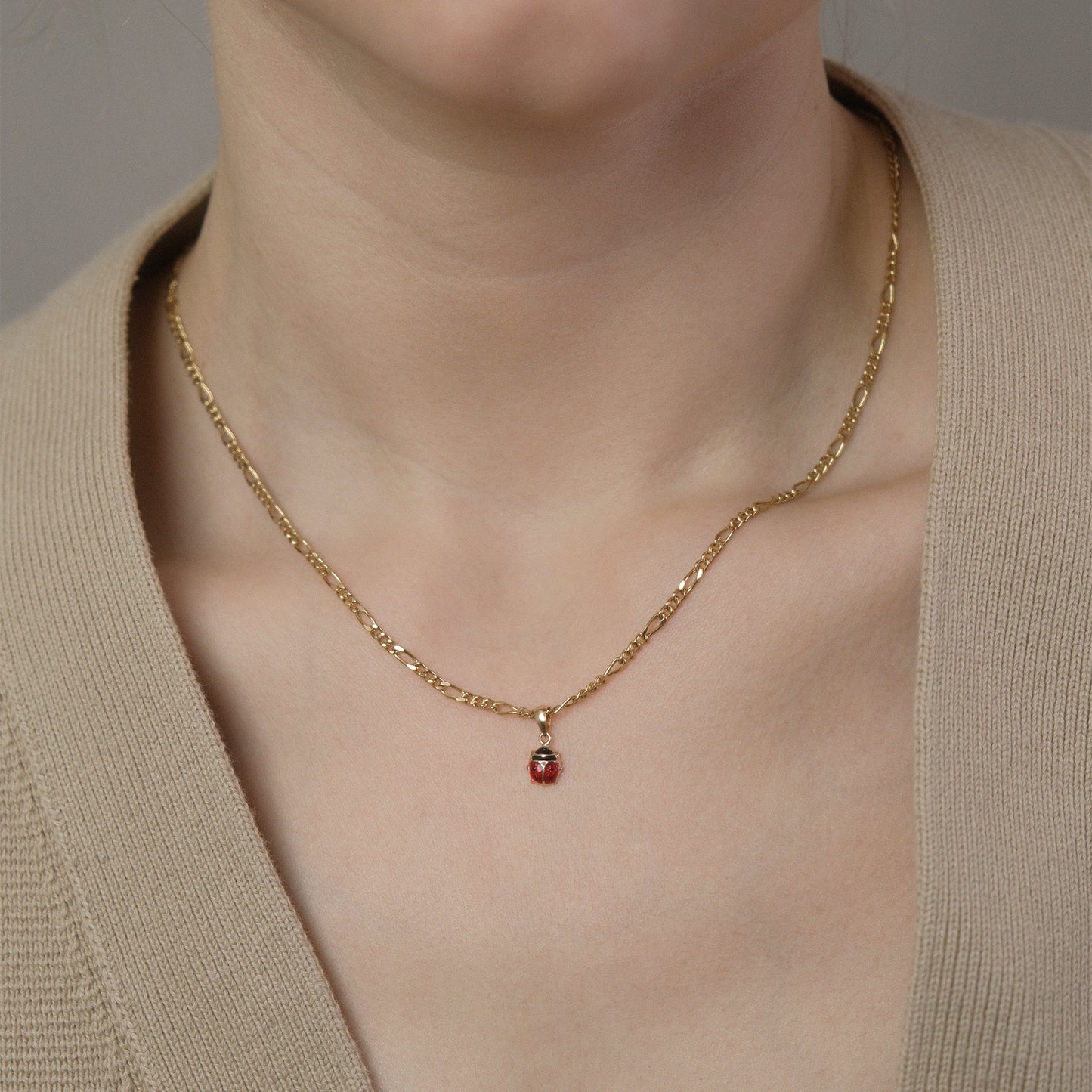 Model trägt eine Figarokette mit Marienkäfer-Anhänger aus 14k Echtgold.