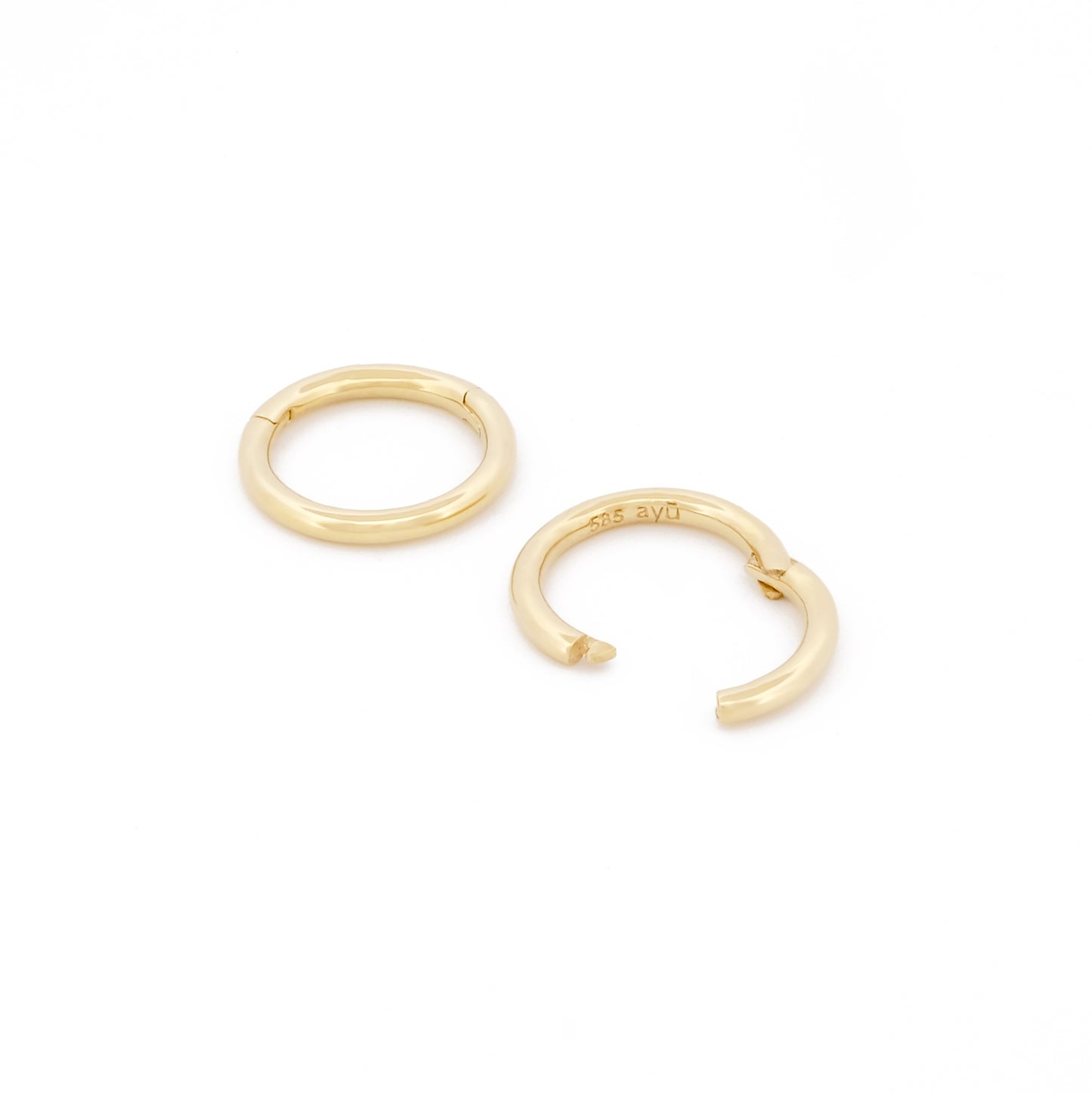 Detailansicht Verschluss des Small Seamless Huggie Hoops aus 14k Gelbgold, liegend auf weißem Hintergrund.