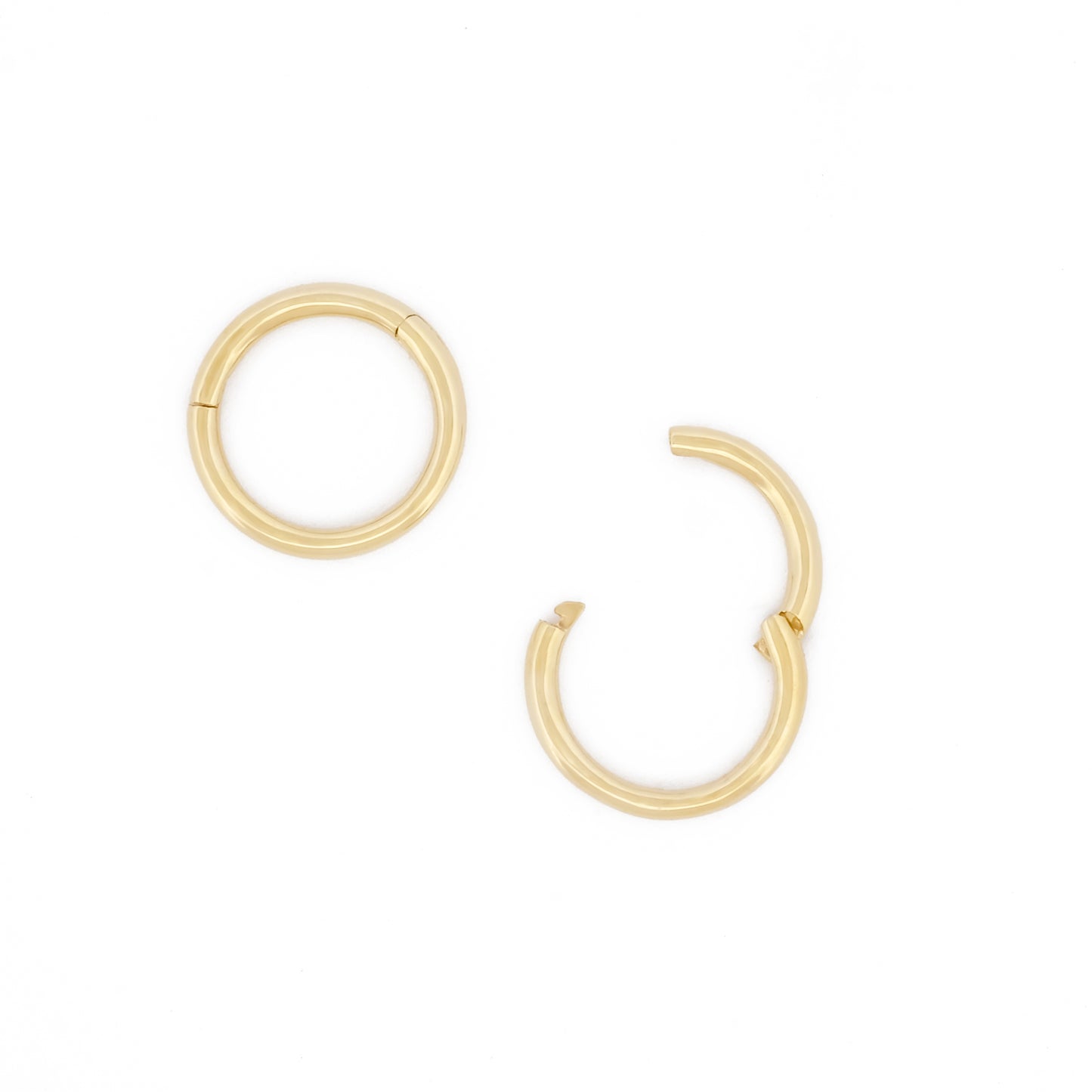 Detailansicht Öffnungsweite des Small Seamless Huggie Hoops aus 14k Gelbgold, liegend auf weißem Hintergrund.