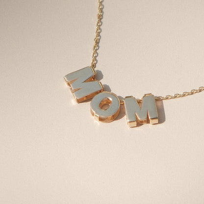 Nahaufnahme: MOM-Buchstabenkette liegend auf grauem Untergrund.