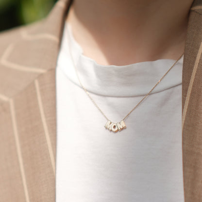 Model trägt eine MOM-Buchstabenkette aus 14k Echtgold.