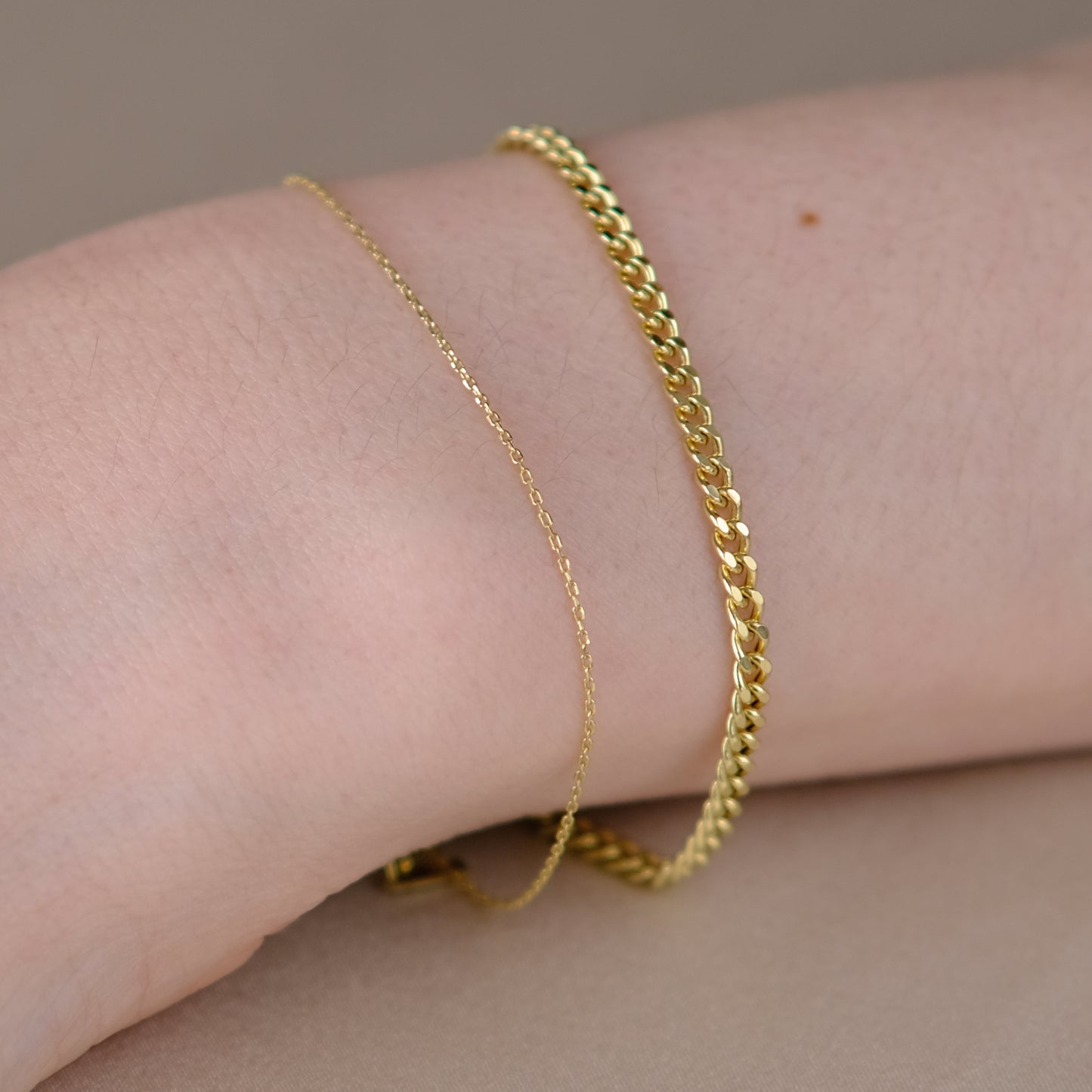 Handgelenk mit zwei Armketten aus 14k Echtgold der Marke ayu – Essential Anchor Bracelet und Curb Bracelet.