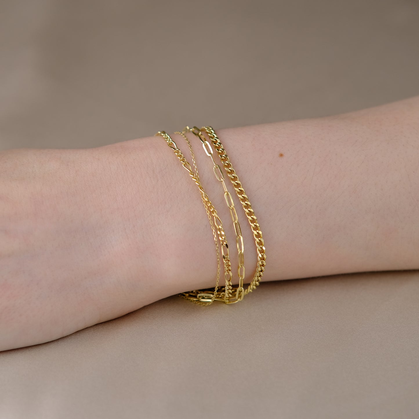 Handgelenk mit vier Armbändern aus 14k Echtgold der Marke ayu.