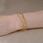Handgelenk mit vier Armbändern aus 14k Echtgold der Marke ayu, die wirr und überkreuzt liegen.