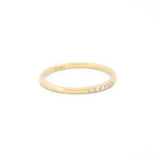 Seitenansicht eines schmalen Rings aus 14k Gelbgold mit 5 weißen Diamanten auf weißem Hintergrund.