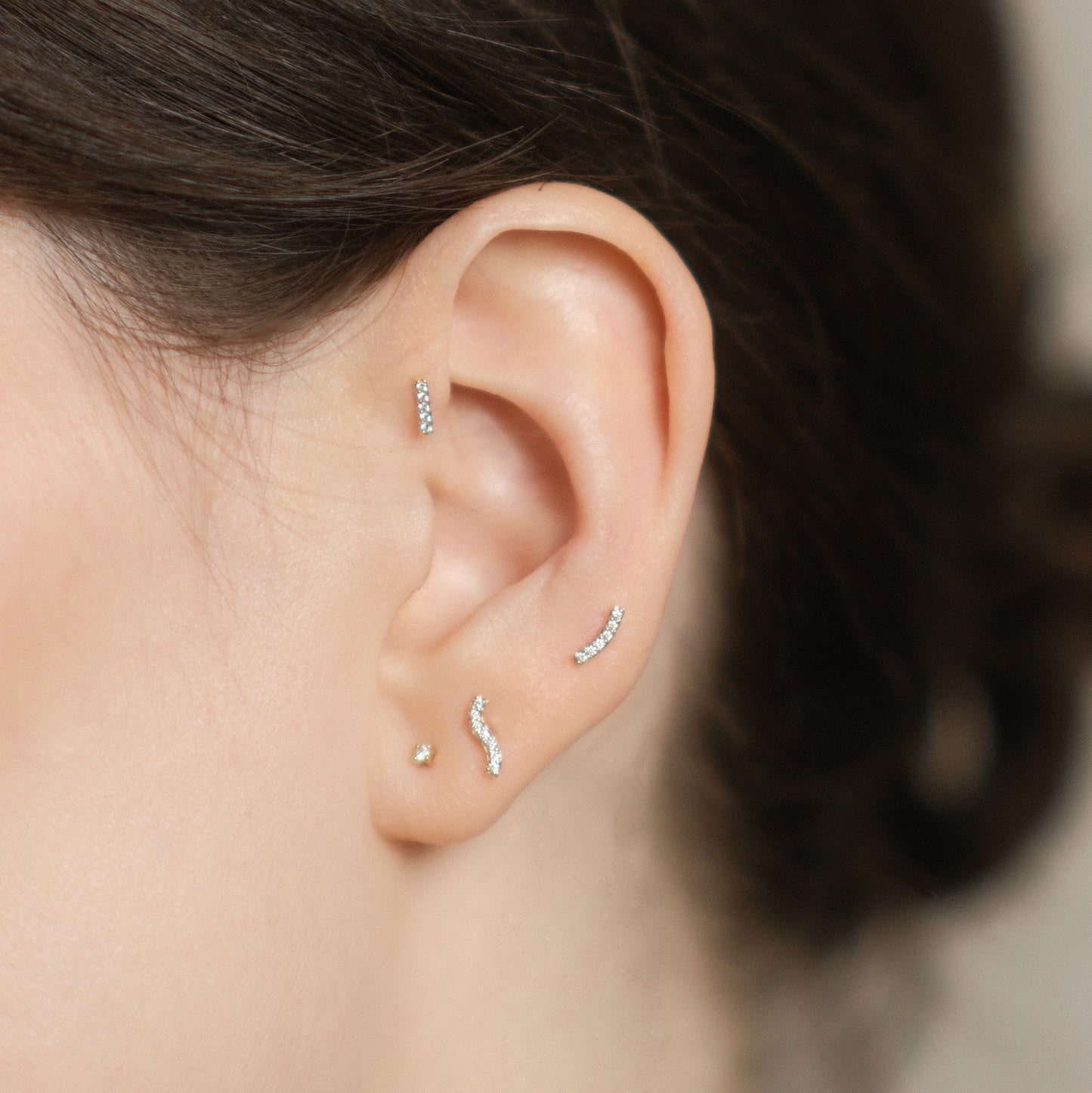 Nahaufnahme: Vier Diamantohrstecker aus 14k Gold, getragen am Ohr eines Models.