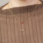 Model trägt eine Kette mit Delfin-Anhänger und darüber eine weitere Kette mit Marienkäfer-Anhänger aus 14k Echtgold.