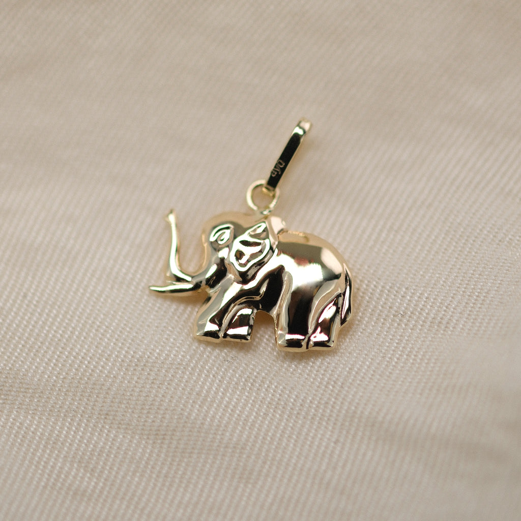 Elefant-Anhänger aus 14k Echtgold auf beigem Untergrund.