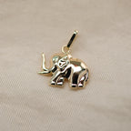 Elefant-Anhänger aus 14k Echtgold auf beigem Untergrund.