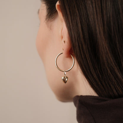 Rückansicht: Model trägt die Classic Hoop Earrings Large mit dem Heart Pendant aus 14k Gold als Einhänger.