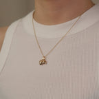 Model trägt eine Kette mit zwei Herz-Anhängern aus 14k Echtgold über weißem Top.