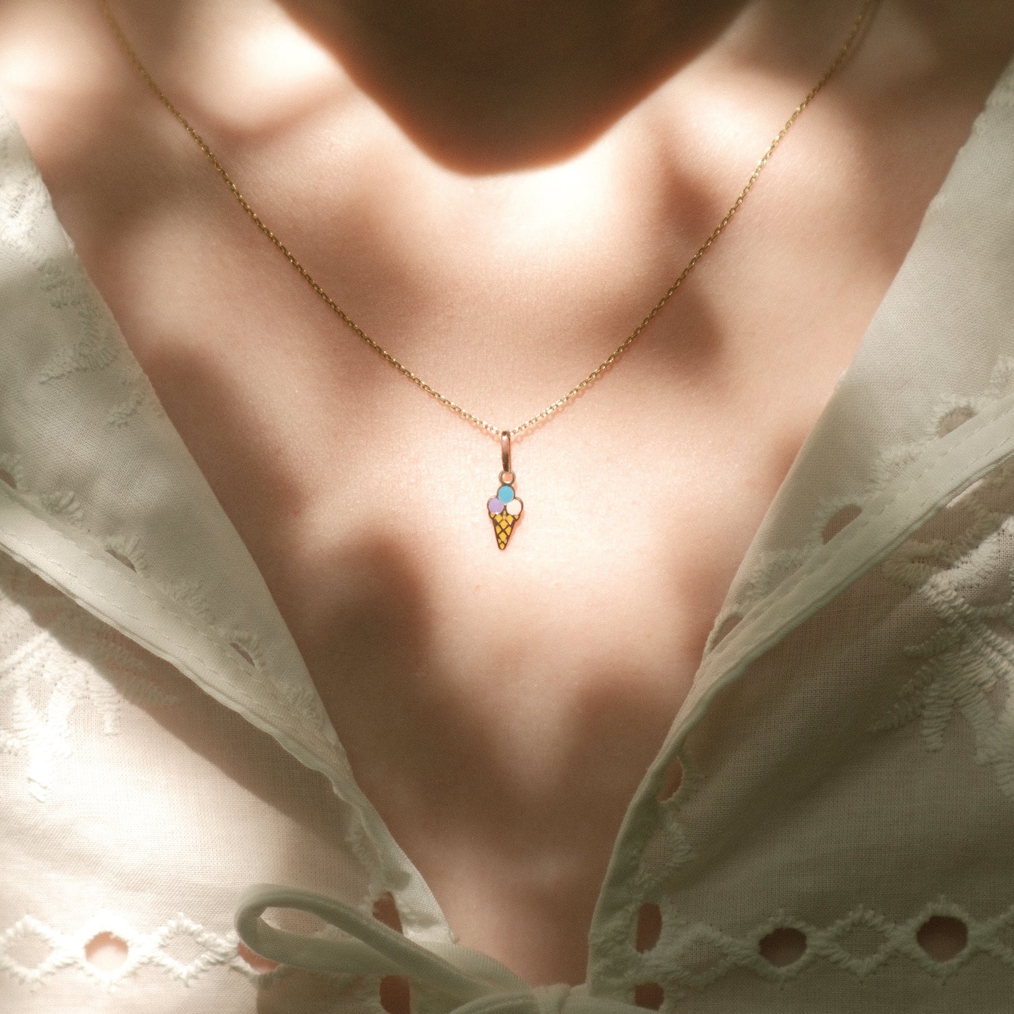 Eis-Anhänger aus 14k Massivgold an einer feinen Kette getragen zu weißem Spitzenoberteil.