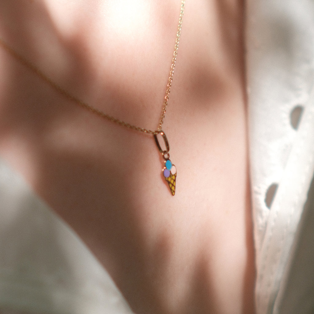 Eis-Anhänger aus 14k Massivgold und Emaille getragen an filigraner Goldkette im Streulicht.