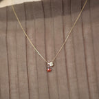 Model trägt eine Kette mit Marienkäfer-Anhänger und dem Buchstaben-Anhänger „S“ aus 14k Echtgold.