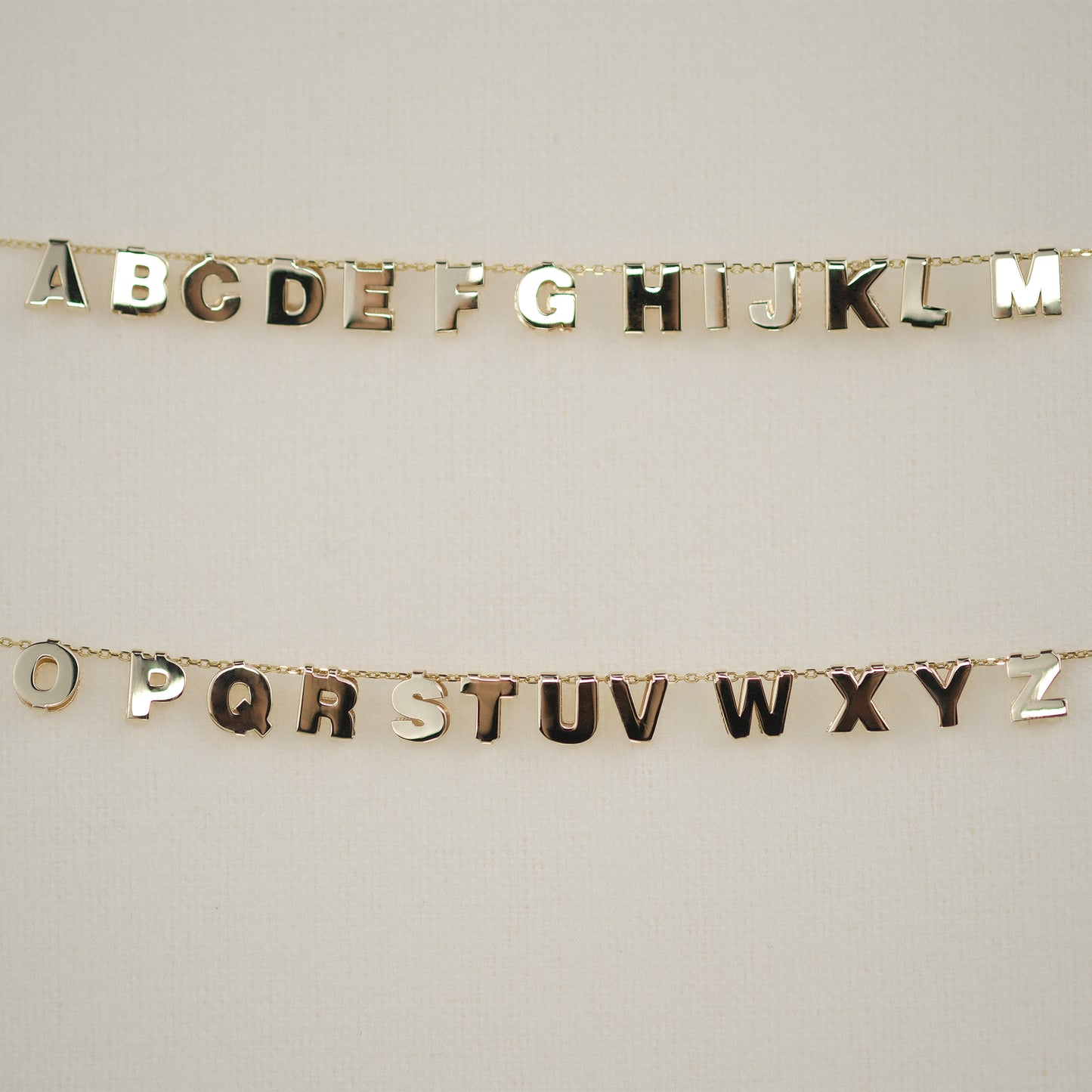 Buchstabenanhänger aus 14k Echtgold A-Z auf Kette aufgereiht.