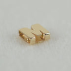 Buchstabenanhänger M aus 14k Echtgold liegend auf weißem Untergrund.