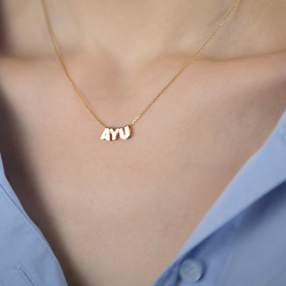 Model trägt die Letter Chain Necklace mit den Buchstabenanhängern „AYU“ aus 14k Echtgold.