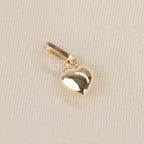 Kleiner Herz-Anhänger aus 14k Echtgold liegt auf beigem Untergrund.