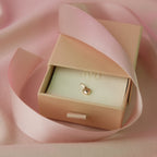 Mini Heart Pendant aus 14k Gold liegt in einer Schmuckschachtel mit rosa Geschenkband.