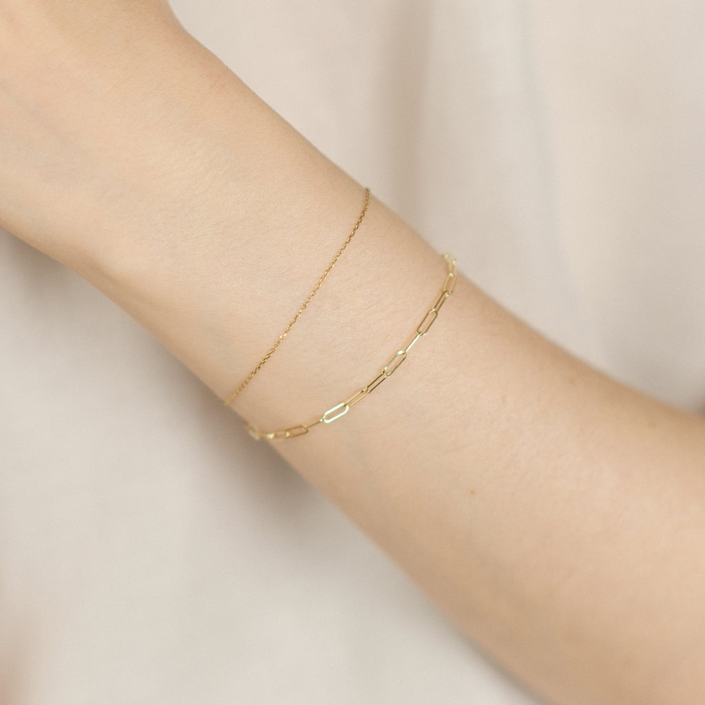 Model trägt Paperclip-Armband kombiniert mit dem Essential Anchor Chain Bracelet aus 14k Gold.
