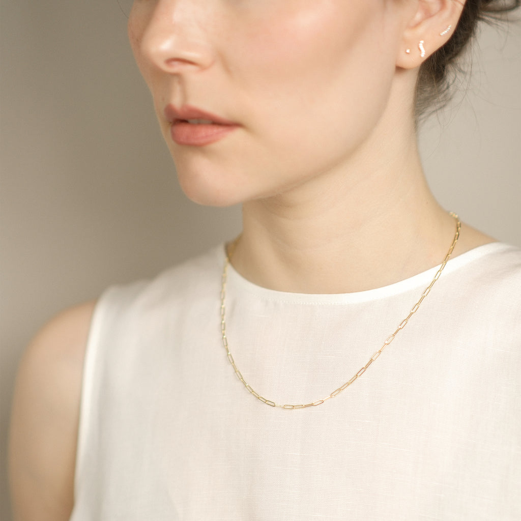 Model trägt elegante Paperclip-Kette aus 14k Gold.