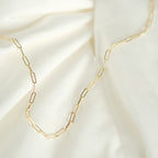 Elegante Paperclip-Kette aus 14k Gold, flach liegend auf weißem Stoff.