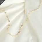 Elegante Paperclip-Kette aus 14k Gold, flach liegend auf weißem Stoff.