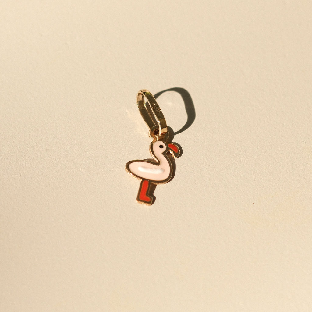 Flamingo-Anhänger aus 14k Massivgold mit rosa und roter Emaille auf beigem Hintergrund.