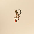 Flamingo-Anhänger aus 14k Massivgold mit rosa und roter Emaille auf beigem Hintergrund.