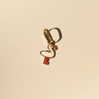 Flamingo-Anhänger aus 14k Massivgold mit rosa und roter Emaille auf beigem Hintergrund.