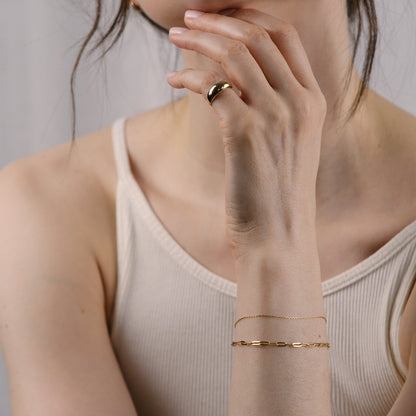 Model trägt Paperclip Chain Bracelet, Essential Anchor Chain Bracelet und Pinky Dome RIng.