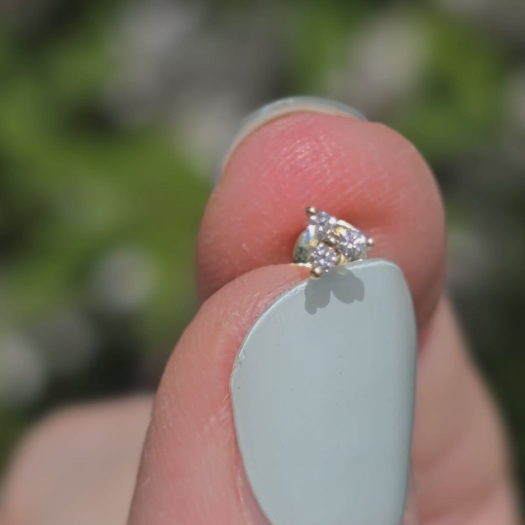 Ohrstecker aus 14k Gelbgold und drei Diamanten funkelt im Sonnenlicht.