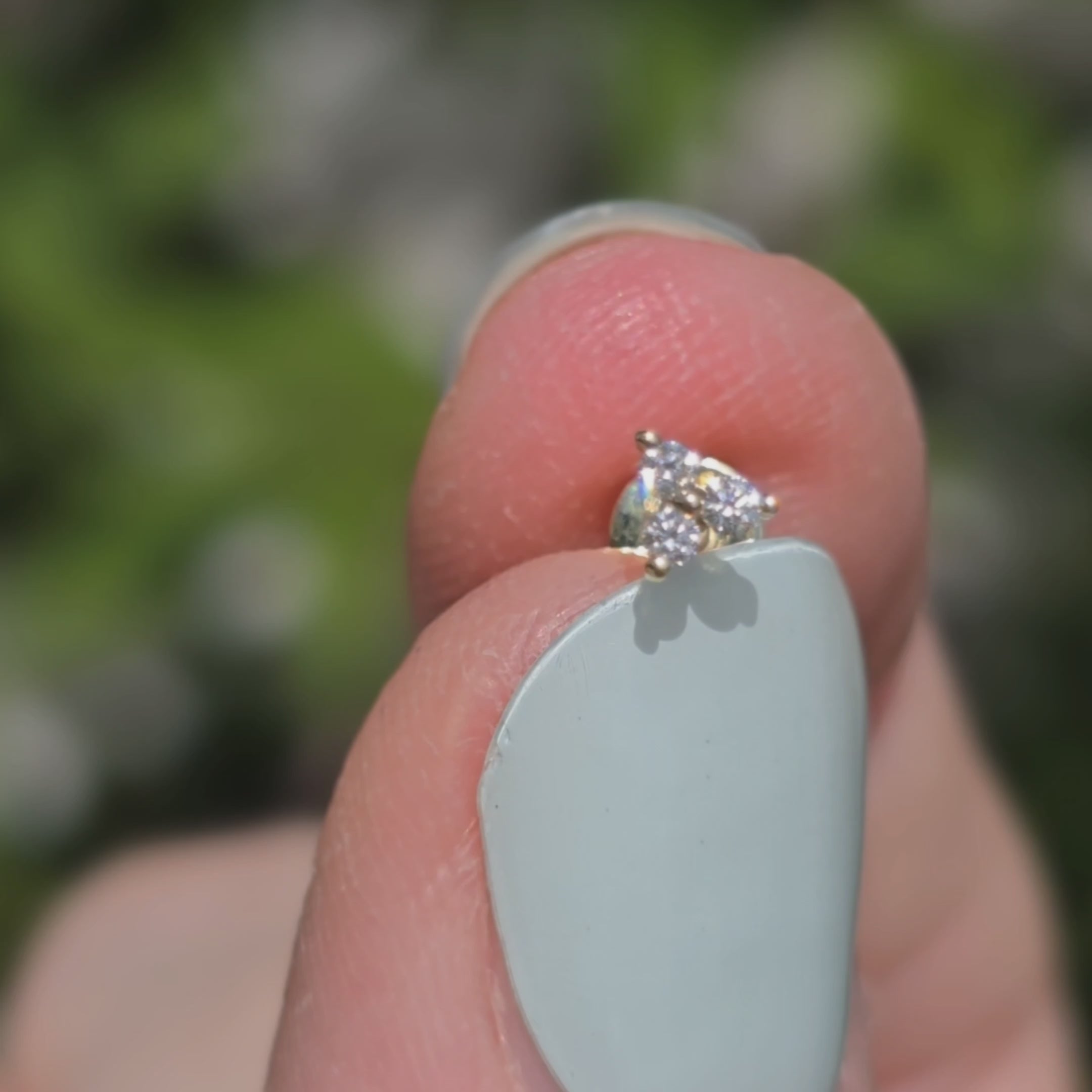 Ohrstecker aus 14k Gelbgold und drei Diamanten funkelt im Sonnenlicht.