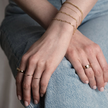 Model überkreuzt die Hände und trägt verschiedene Ringe und Armketten aus 14k Echtgold der Marke ayu.